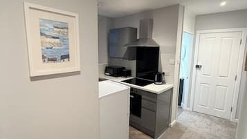 Une cuisine compacte équipée d’un four, d’un micro-ondes et d’une cuisinière intégrés, d’un petit réfrigérateur et d’un évier.