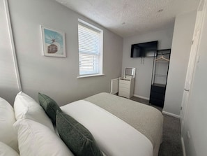 Um quarto com cama, penteadeira, espelho e janela com persianas.
