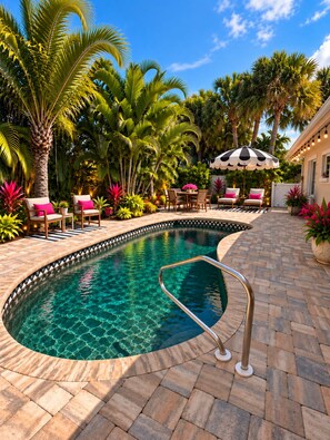 A swimming pool with a tiled deck, surrounded by palm trees and chairs. - Tropical Oasis in dowtown 2 blocks from the Harbor (Punta Gorda)
