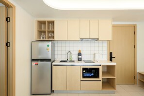 Une cuisine moderne dotée d’un réfrigérateur en acier inoxydable, d’un lave-vaisselle encastré et d’armoires en bois.