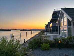 Una propiedad frente al agua con una casa moderna, balcón y vistas al mar.