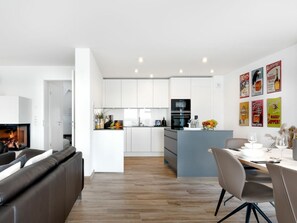 Una cocina moderna con armarios blancos, una isla central y un comedor con mesa y sillas.