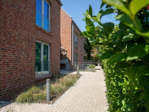 A brick building with large windows and a paved pathway. - 248 - Apartment Anchorage (Juist)