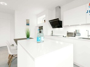 A modern kitchen with white cabinetry, a central island, and a built-in microwave. - 248 - Apartment Anchorage (Juist)