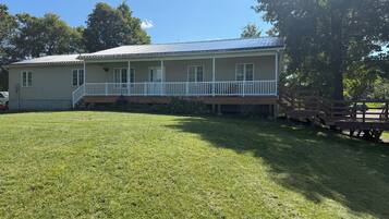 A two-story house with a front porch and a covered deck area.