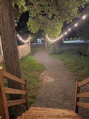 A pathway leading to a building with string lights overhead.