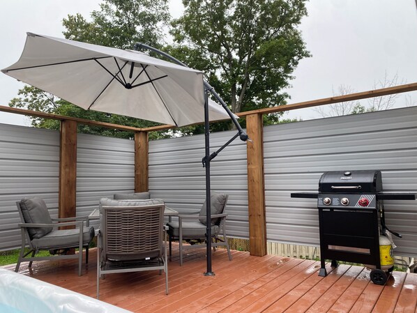 An outdoor patio with a grill, umbrella, and seating area.