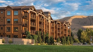 A multi-story hotel with balconies, a stone facade, and a mountainous backdrop. - WM BLOCK Lake House 1br dlx (Chelan)