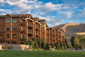 A multi-story hotel with balconies, a stone facade, and a mountainous backdrop. - WM BLOCK Lake House 1br dlx (Chelan)