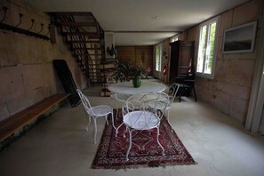 A room with a round table and four chairs, a staircase, and a wooden cabinet. - Le Gué Renard: A Balcony Overlooking the Charente. Pets allowed. (Jarnac)