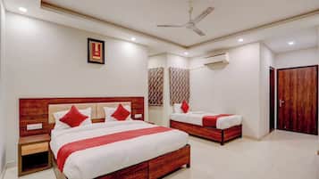Une chambre d’hôtel avec un grand lit, un lit plus petit, une table de chevet, un ventilateur de plafond et un appareil de climatisation.