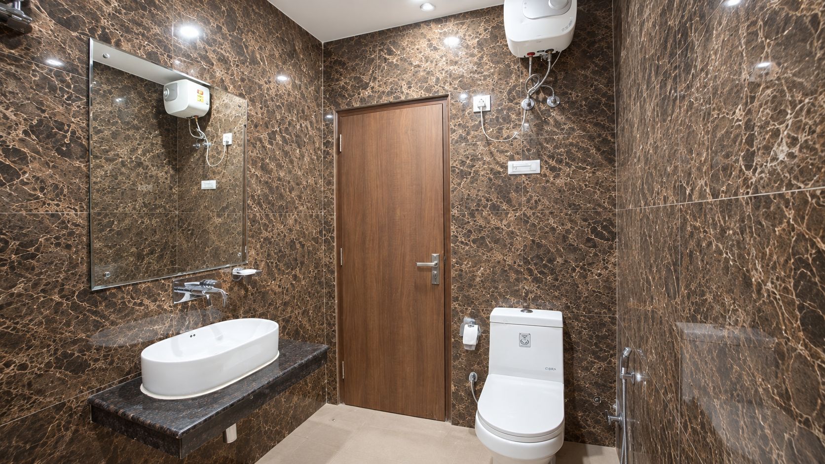 Ein Badezimmer mit Marmorwand, Holztür, Waschbecken in Weiß und Toilette.