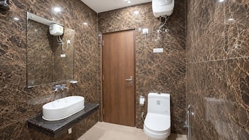 Ein Badezimmer mit Marmorwand, Holztür, Waschbecken in Weiß und Toilette.