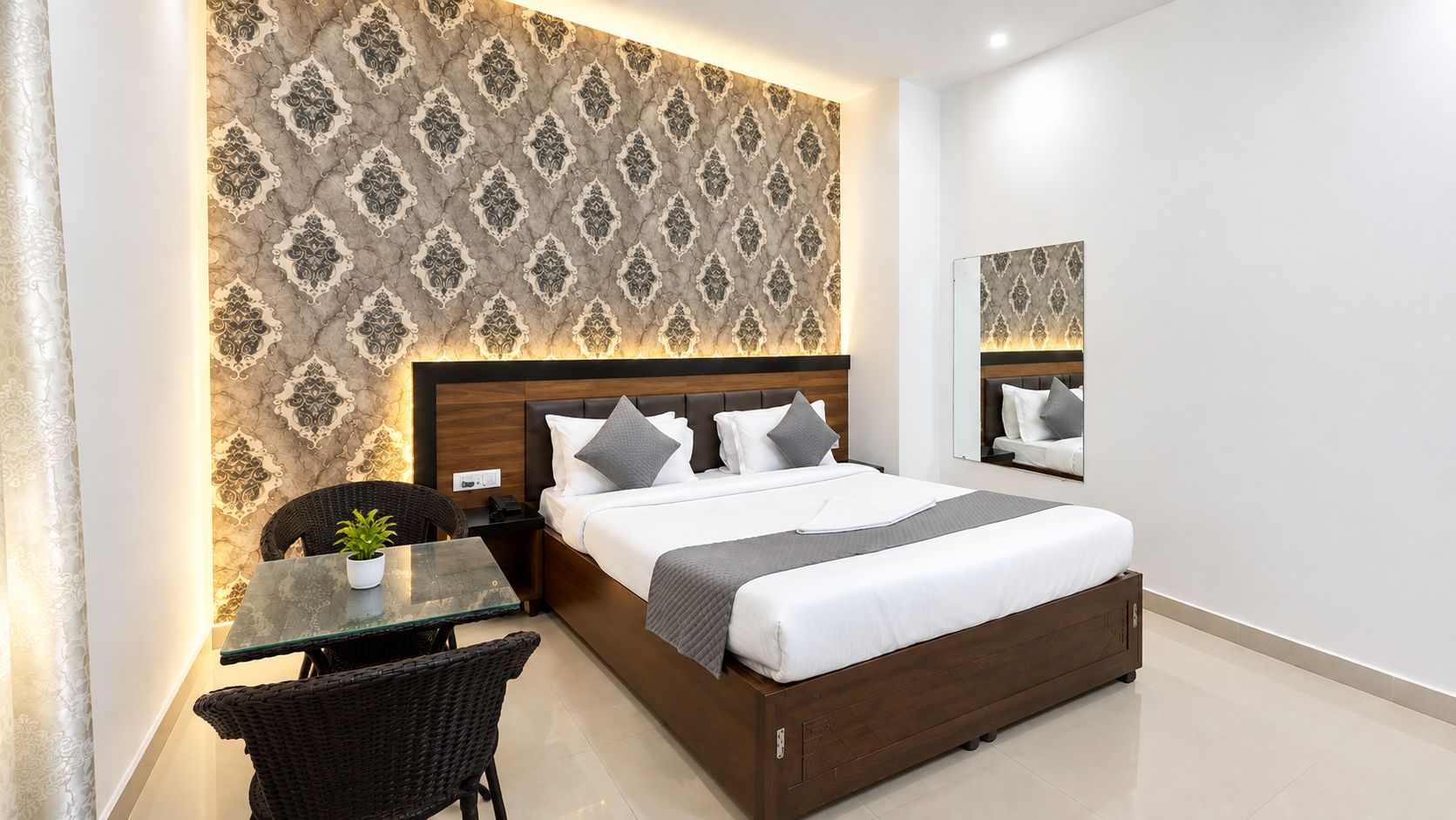 Ein Hotelzimmer mit Bett, Nachttisch, Tisch mit Stuhl und Spiegel an der Wand.