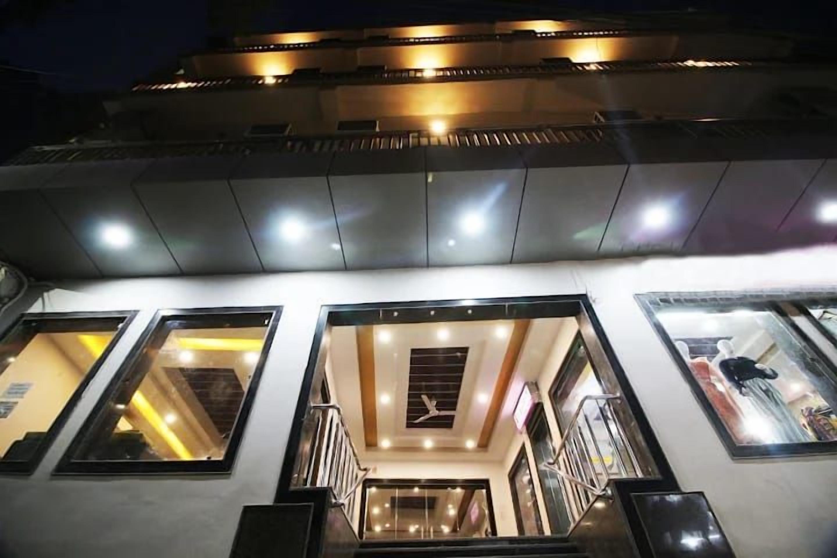 A hotel interior with multiple floors, a central staircase, and a view of the sky through the windows.