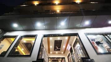 A hotel interior with multiple floors, a central staircase, and a view of the sky through the windows.