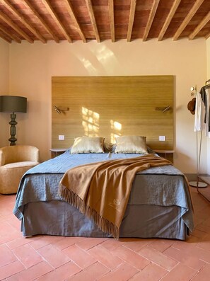 A bedroom with a bed, a chair, a lamp, and a wardrobe. - Casale Tre Dame - Appartamento Il Convivio (Castiglion Fiorentino)