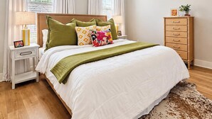 A bedroom with a bed, a nightstand, a dresser, a ceiling fan, and a window with curtains. - The Archie, 2mi to Campus & Sq Velvet Ditch Villas (Oxford)
