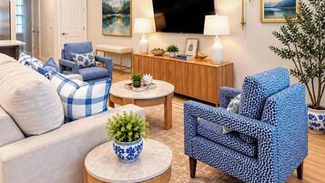A living room with a sofa, two armchairs, a coffee table, a TV, and a plant.