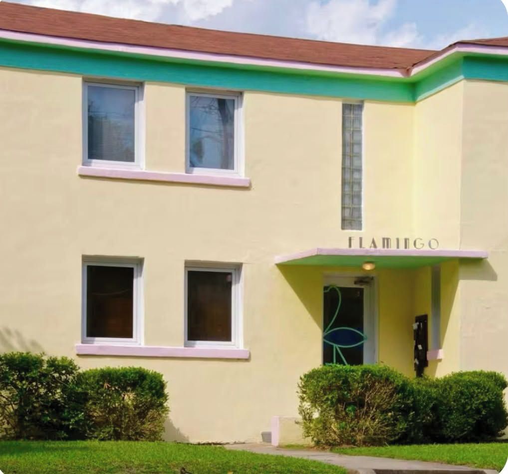 A building with a flat facade, two visible windows, and a sign reading 'FLAMIGO'.