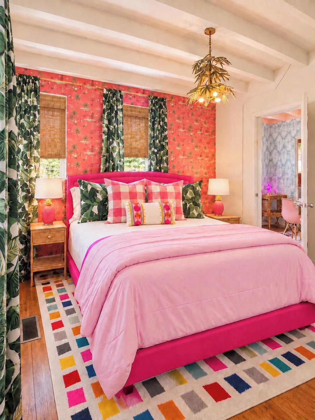 Ein Schlafzimmer mit einem rosa Bett, gemusterten Vorhängen und einem farbenfrohen Teppich.