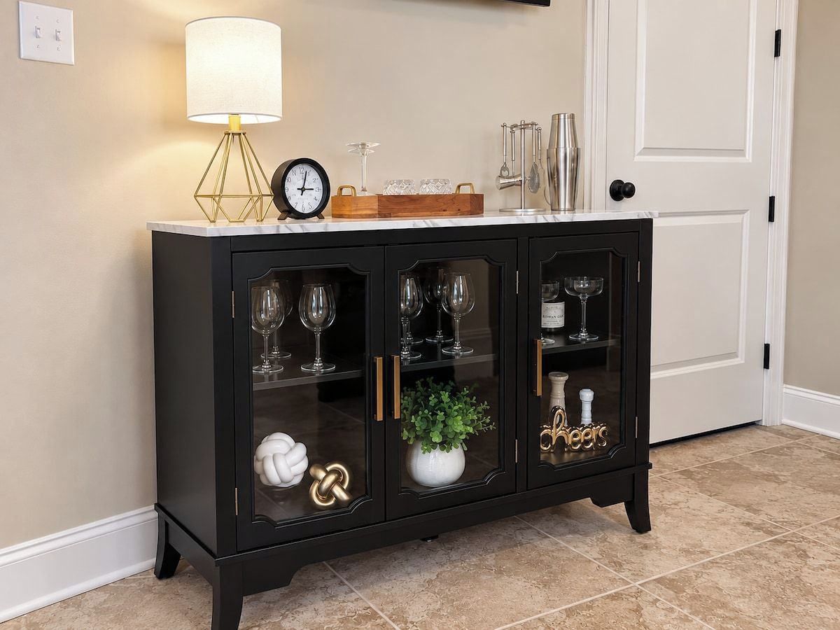 A black glass-fronted cabinet with wine glasses, a clock, and decorative items.