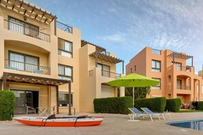 Ein Hotel mit Schwimmbad, Terrassensitzgelegenheiten und einem Boot.