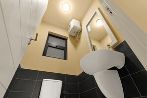 Ein Badezimmer mit Toilette, Waschbecken, Spiegel und einem an der Wand befestigten Seifenspender.