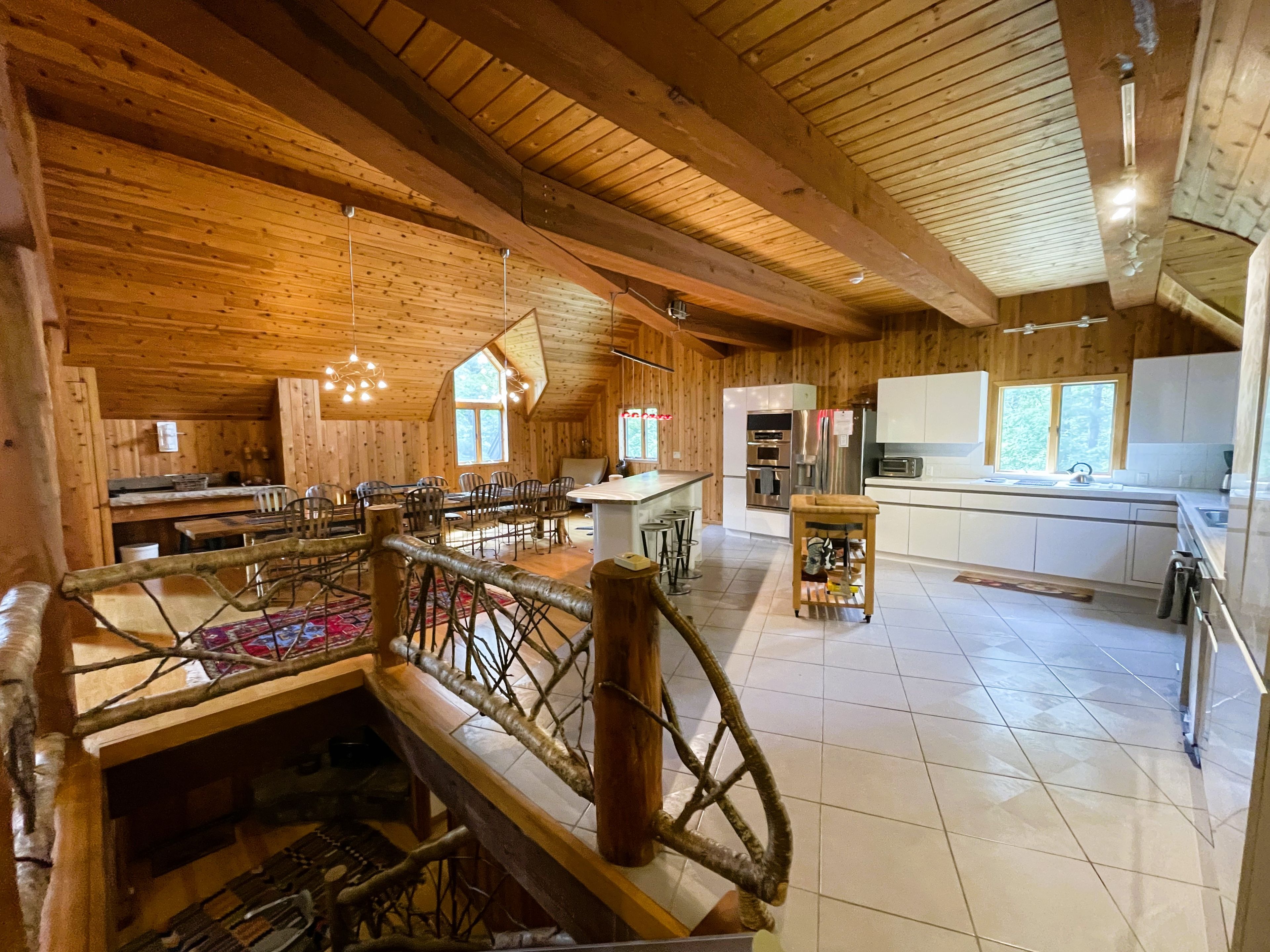 A spacious wooden interior with a dining area, kitchen, and a staircase.