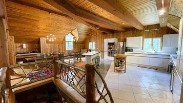 A spacious wooden interior with a dining area, kitchen, and a staircase.