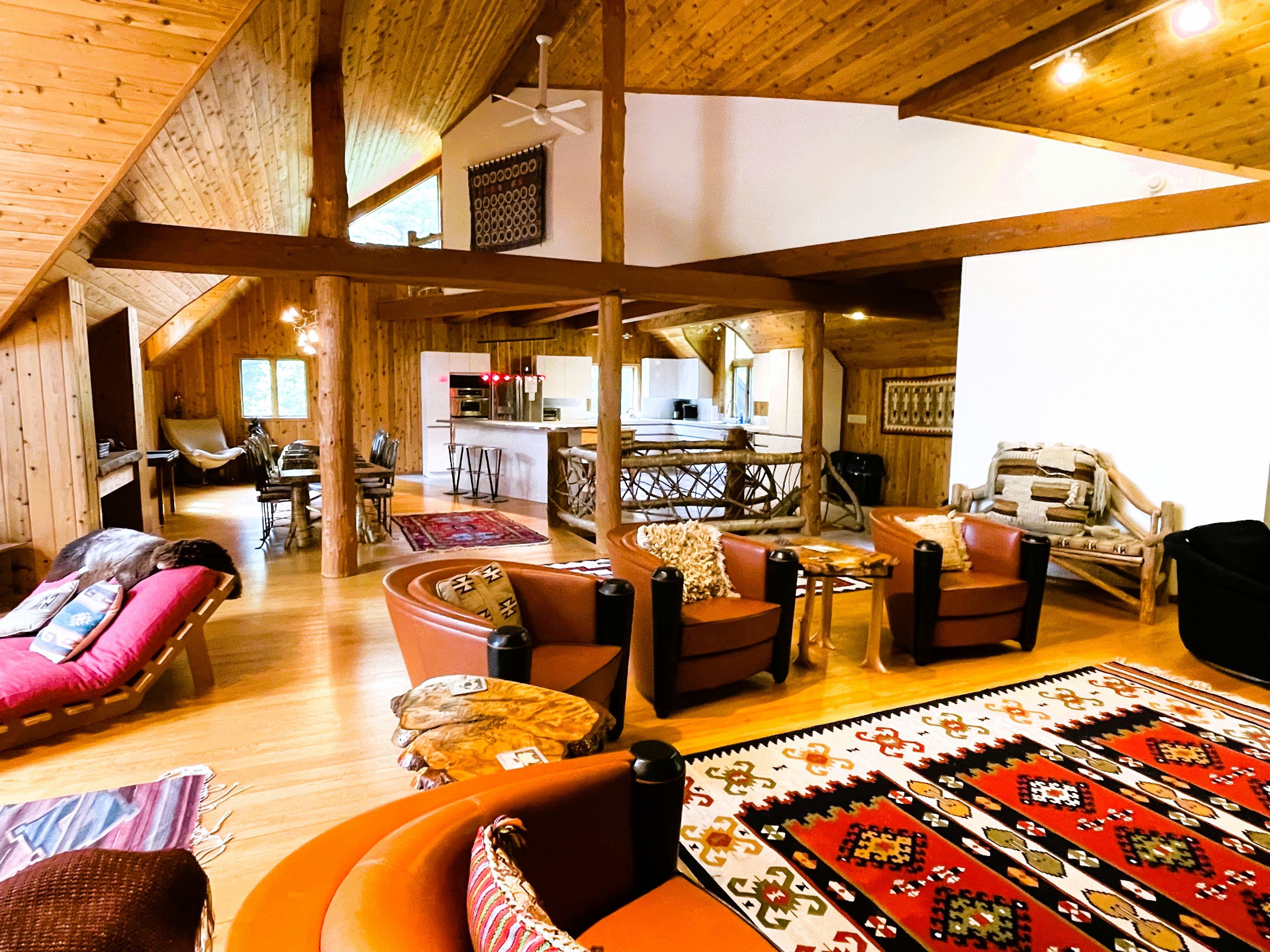 Un intérieur spacieux en bois comprenant un coin repas, une cuisine et un salon avec de nombreux espaces pour s’asseoir.