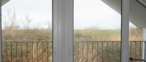 Una habitación con techo inclinado y ventanas amplias con vista a un campo cubierto de hierba.