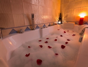 A bathtub filled with bubbles and rose petals, a bottle of champagne, and a candle on a side table. - Almerian Holiday Home for 4 (Laroya)
