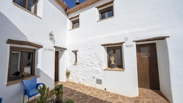 Un patio con un edificio blanco, una silla azul y plantas en macetas.
