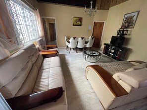 A living room with a sofa, a coffee table, and a dining area with chairs.