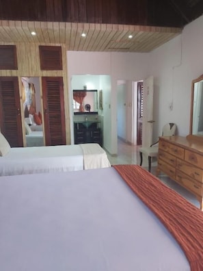 A bedroom with two beds, a wooden dresser, and a mirror.