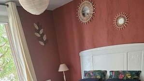 Un dormitorio con una cama, una mesita de noche, una lámpara y un ventanal con cortinas.