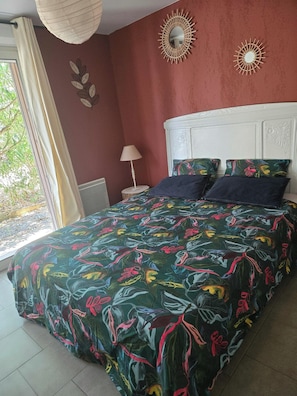 Une chambre à coucher avec un lit, une table de chevet, une lampe et une fenêtre avec des rideaux.