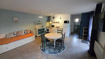 A compact kitchen with a dining area, a sofa, and a television.