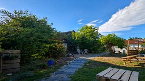 Un jardín con un banco de madera, una mesa de picnic y un camino que lleva a una casa.