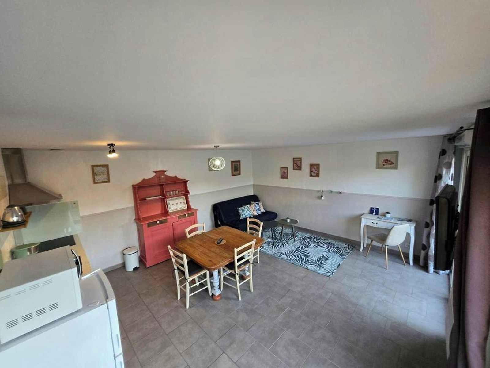 Un espacio habitable compacto con comedor, kitchenette y pequeño escritorio.