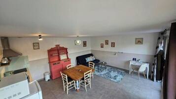 Un espacio habitable compacto con comedor, kitchenette y pequeño escritorio.