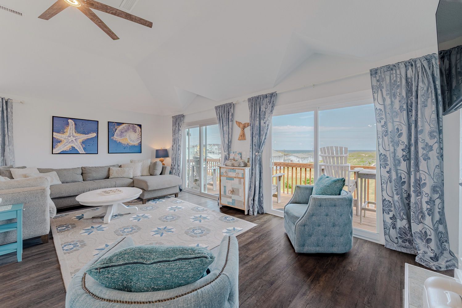A spacious living room with a large window, a sofa, a coffee table, and a view of the outdoors.