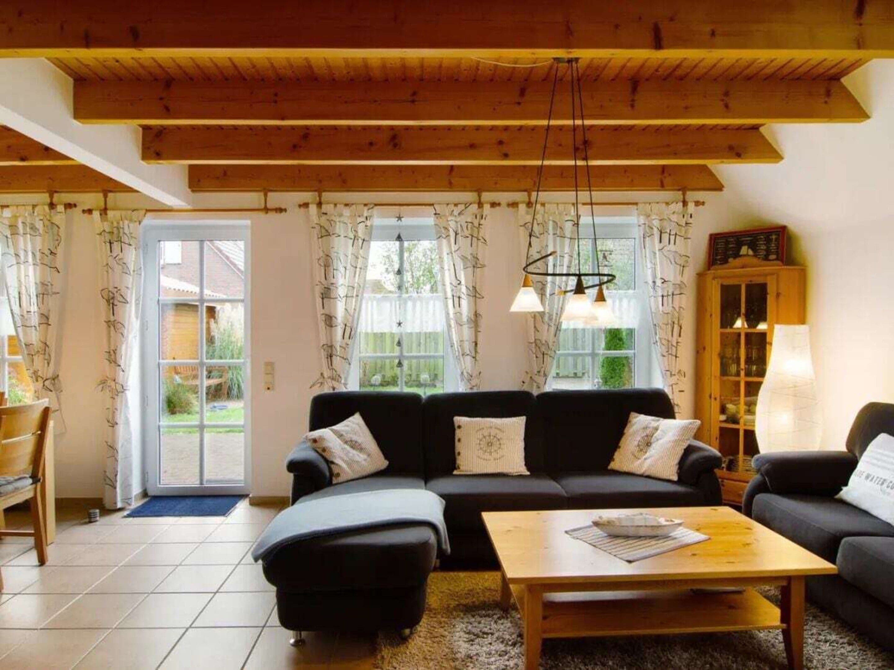A living room with a wooden ceiling, a sofa set, a coffee table, and a cabinet with a lamp.