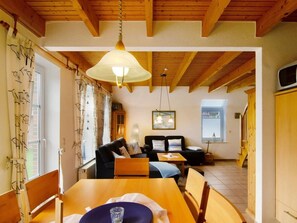 A cozy room with a wooden ceiling, a dining table with chairs, a sofa, and a television. - Holiday Home With 3 Bedrooms (Dornum)