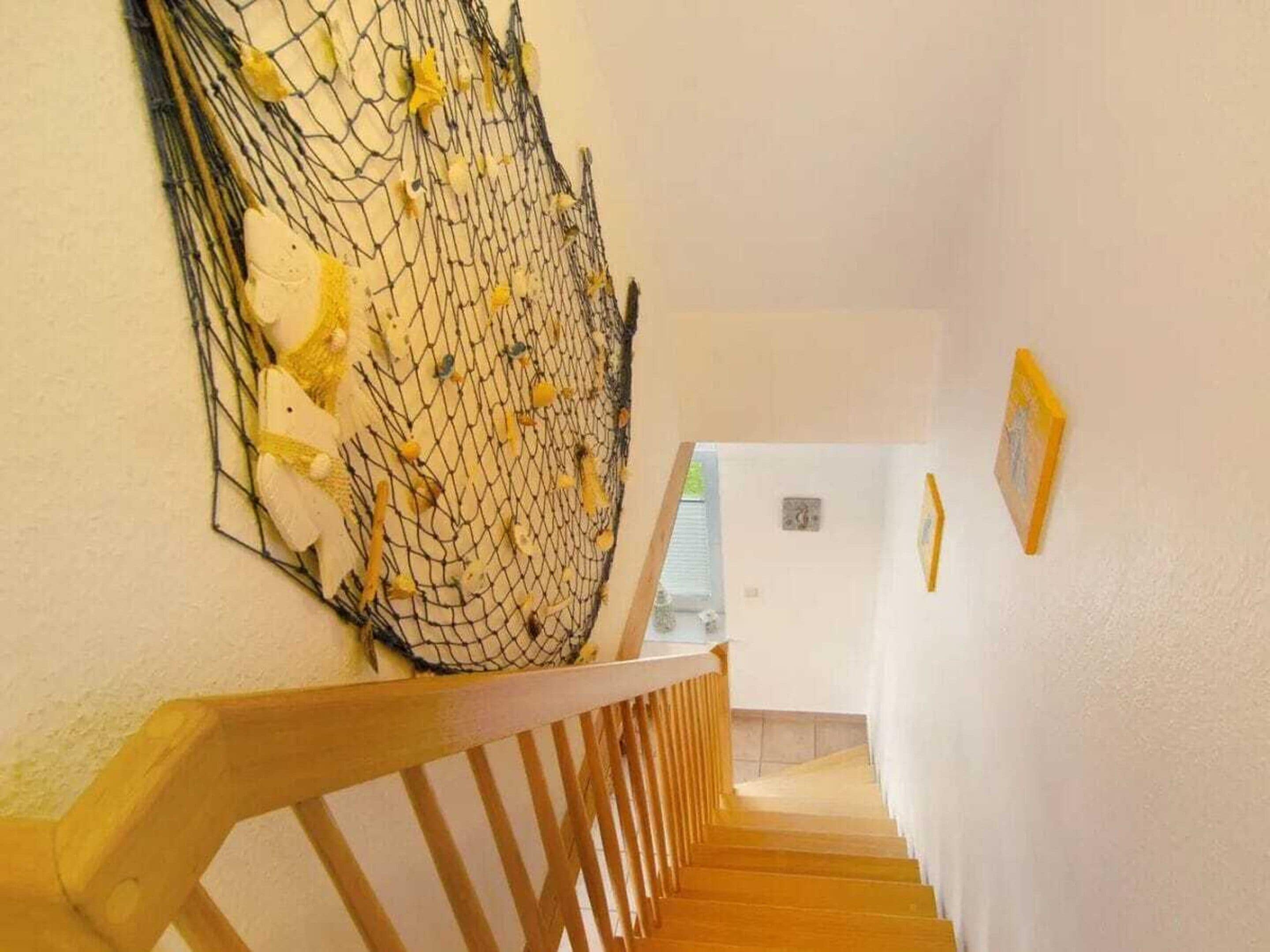 A staircase with a wooden handrail and a net-like structure attached to the wall.