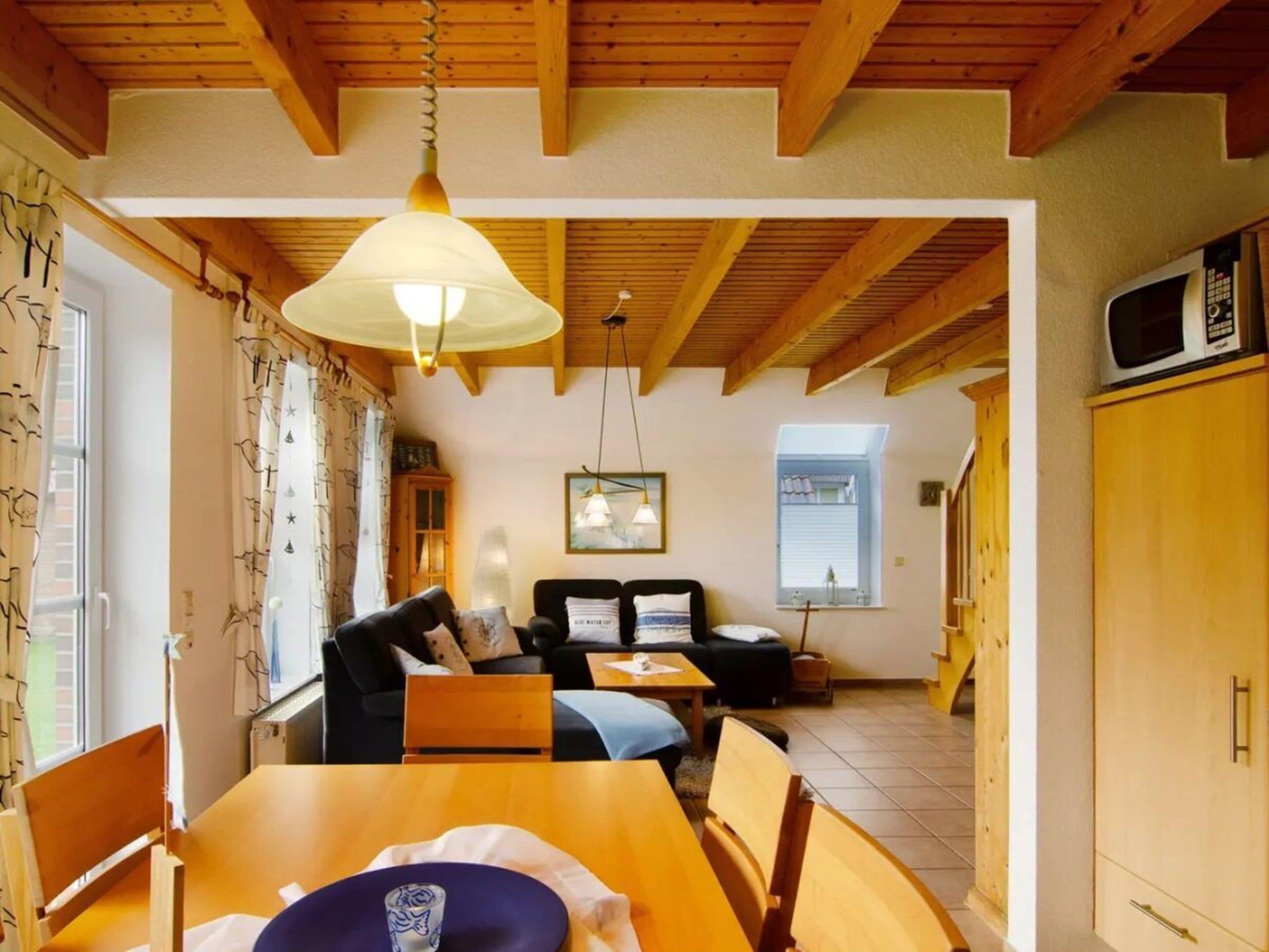 A cozy room with a dining table, chairs, a sofa, and a kitchen area with a microwave.