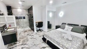 Ein modernes Schlafzimmer mit einem großen Bett, einem Schreibtisch, einem Stuhl und einem begehbaren Kleiderschrank.