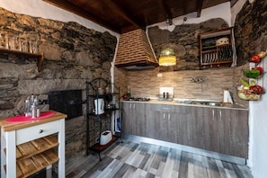 Eine Küche mit Steinwänden, einer Holz Arbeitsplatte und einer hängenden Leuchte.
