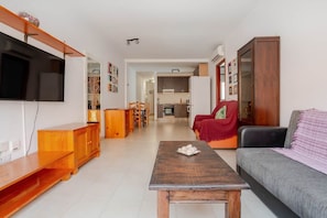 Ein Wohnzimmer mit Fernseher, Holzmöbeln, einer Couch und einem Couchtisch.